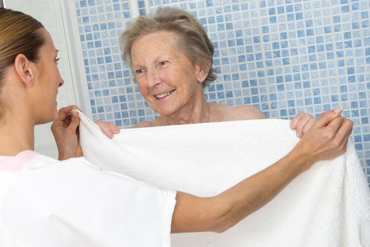 Older woman getting out of the shower with help from carer