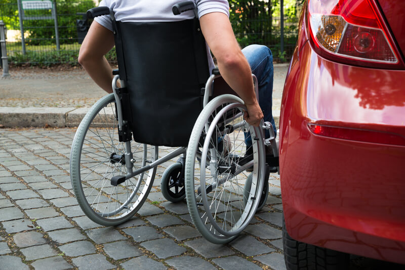 Wheelchair user next to a car