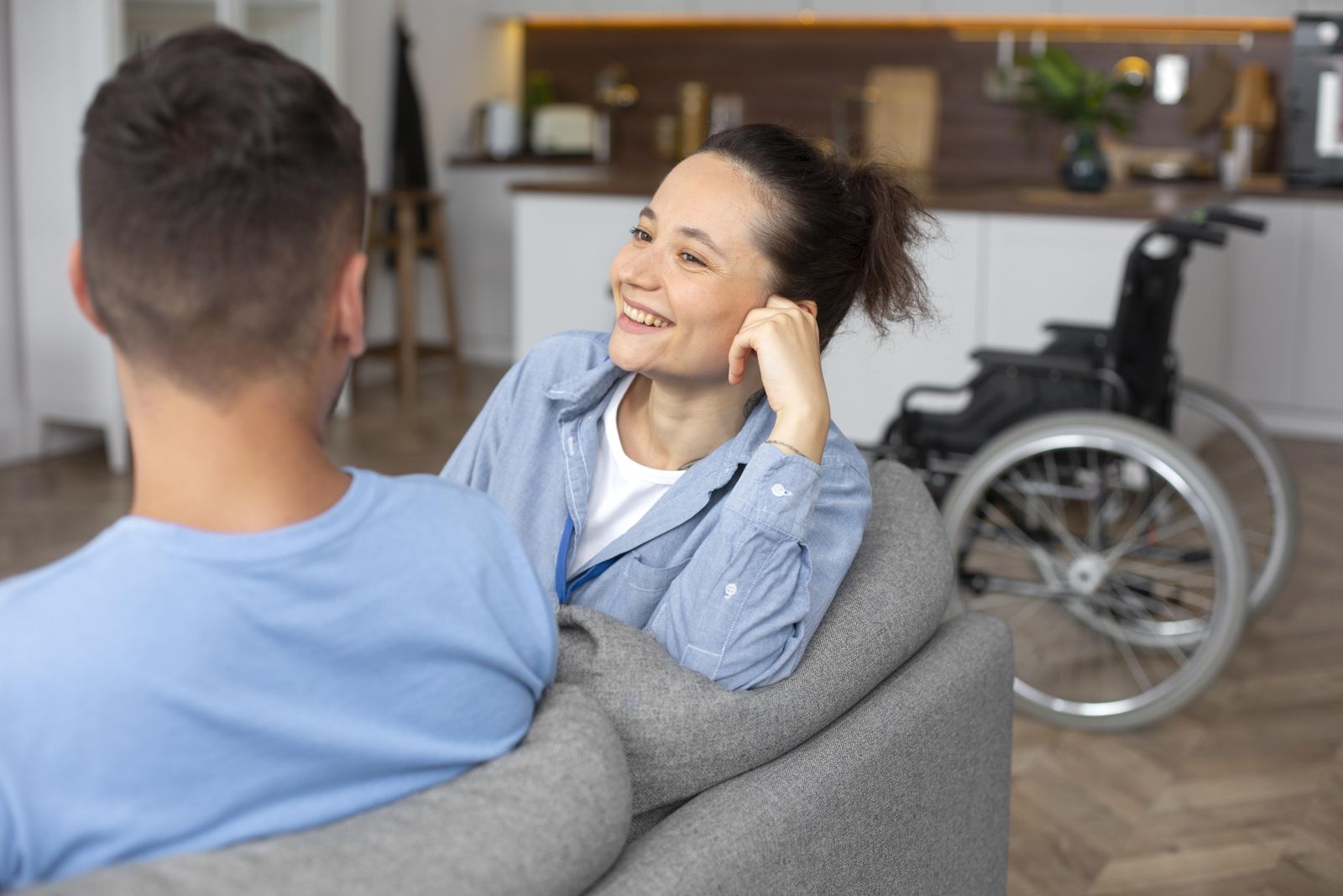 couple sitting on a couch talking with a wheelchair in the background